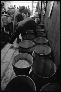 Older customer sampling goods from a bulk food barrel, Erewhon Trading Company