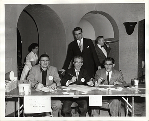 Four unidentified men at a registration table